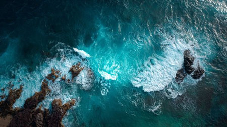 Aerial view of the ocean with waves crashing on the rocks.の写真素材