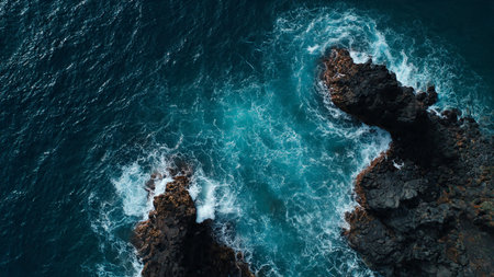 Aerial drone view of ocean waves crashing on the rocky shore.の写真素材
