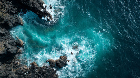 Aerial view of ocean waves crashing on the rocky shore. Top view