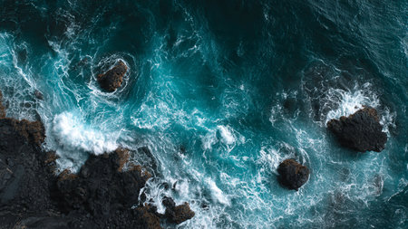 Aerial view of the ocean with waves crashing on the rocks.