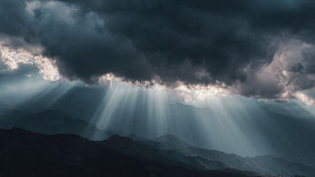 Sun rays shining through dark storm clouds in the mountains, panoramaの写真素材