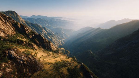 A mountainous valley with a river flowing through it, surrounded by rocky cliffs and lush greenery.の写真素材