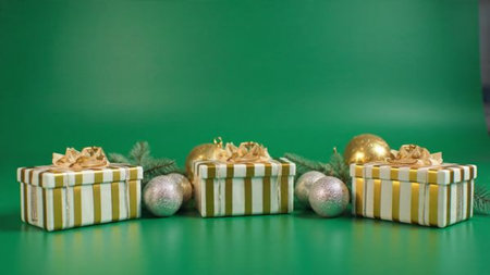 Christmas gift boxes with golden and silver balls and fir branches on green background
