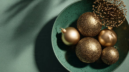 Golden Christmas balls in a bowl on a green background with copy spaceの写真素材