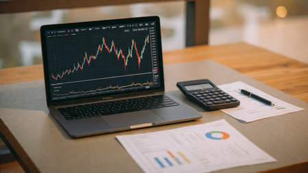 A laptop running live trading platforms with paperwork and hot coffee nearby.の写真素材