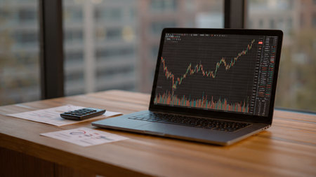 A digital trading station filled with laptop graphs and coffee resting next to analytical documents.の写真素材