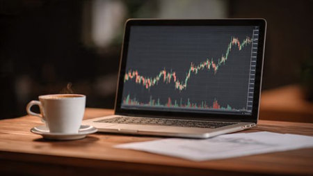 Market analytics on laptop alongside financial summaries and coffee on wooden desk.の写真素材