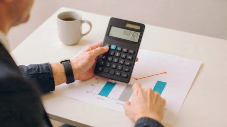 A wooden trading workspace centered on laptop analytics, research papers, and a steaming coffee mug.の写真素材