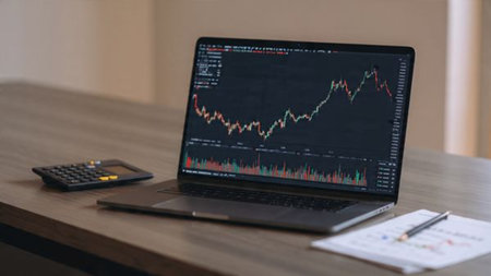Real-time financial analytics fill the laptop screen beside economic documents and a cozy coffee cup on a wooden surface.の写真素材