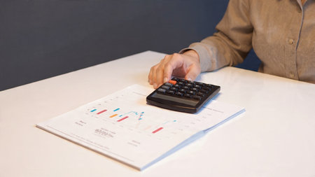 A wooden desk supports a laptop with economic graphs, adding coffee and documents to the analytical scene.の写真素材