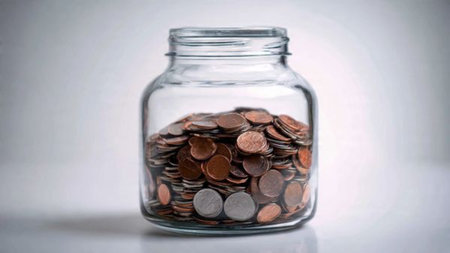 Clean modern savings illustration showing a half-empty jar with a few coins beside it.