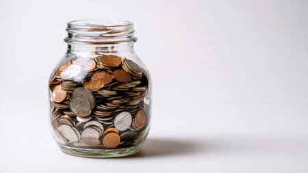 Soft-light wealth concept showing a jar next to ordered coin stacks on an even white background,...