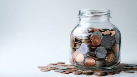 Elegant high-key image showing three coins beside a clear standing jar, commercial-safe.の写真素材