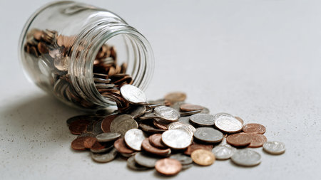 Clean financial planning image with a half-empty jar and coins laid out in a tidy arrangement,...