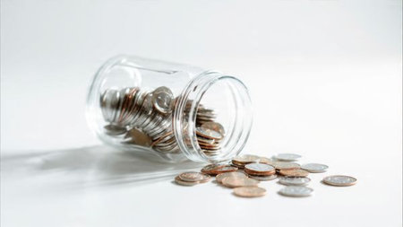 Clean budgeting concept with a transparent jar standing upright next to a neat pile of polished...