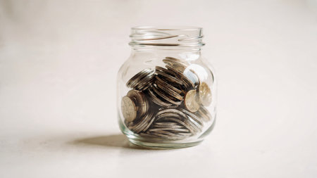 High-key scene showing a tipped jar releasing coins in a flowing straight line.の写真素材
