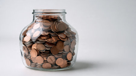 Minimal aesthetic with a transparent jar aligned beside stacked coins under smooth lighting,...