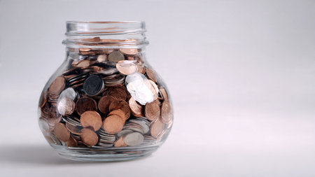 Minimal budgeting theme showing a single coin resting near a clear jar on white background.