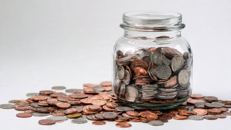 High-key wealth display with a tipped jar and coins scattered in a controlled manner,...