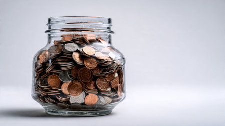 Clean savings concept showing a jar at an angle with coins grouped neatly in front, commercial-safe.の写真素材