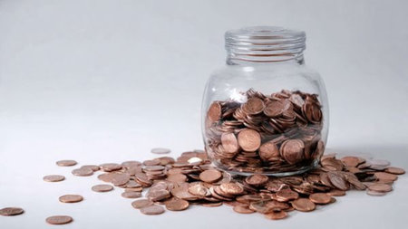 Neat wealth-building scene with coins forming a small pile in front of a transparent jar illuminated...