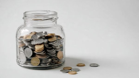 Simple savings flat lay with neatly stacked coins and an upright jar in the center, commercial-safe.