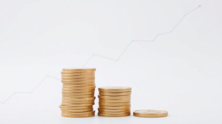 Stacks of coins on a white background with a graph in the backgroundの写真素材