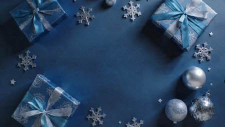 Frosted winter flat lay with shimmering silver snowflakes arranged over a deep, cool-toned blue background.の写真素材