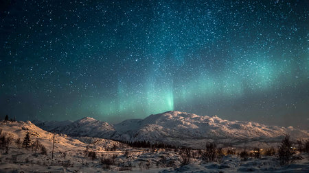 Aurora borealis in the night sky above the snowy mountains
