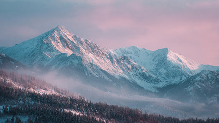Sunrise paints delicate hues on snow-covered mountains in a winter photography style.