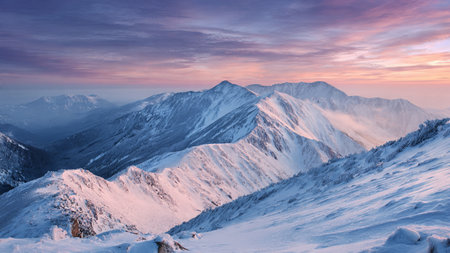 A thin veil of morning haze softens the pastel-lit, snow-covered ridges.