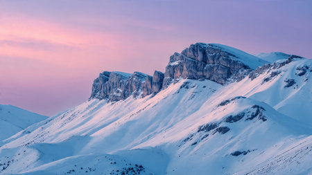 Wisps of morning mist drift across snow-laden peaks, glowing beneath delicate sunrise colors.