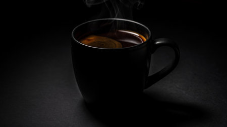 Cup of black tea with smoke on a black background. Selective focus.