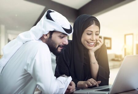 lovely Arabic Couple sitting using laptop looking for new house.の写真素材