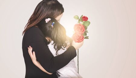 Happy mother's day! Child daughter congratulates mom and gives her flowers tulips. Mum and girl hugging. Family holiday and togetherness.の写真素材