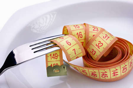 fork and measuring tape on white plateの写真素材