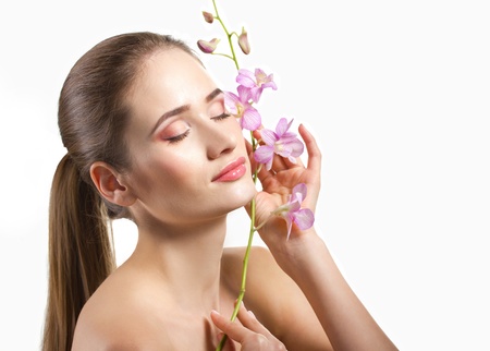 close-up portrait of a beautiful young woman with branch of flowers isolated on whiteの写真素材