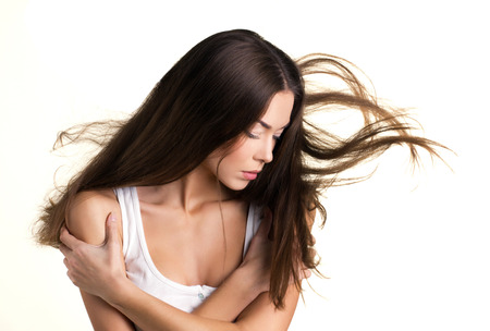 portrait of a young beauty woman with flying long broun hair on white backgroundの写真素材