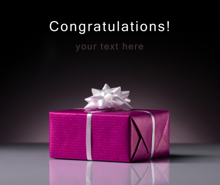 pink present box with white bow on grey and black backgroundの写真素材