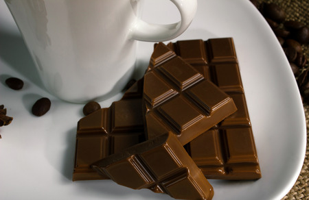 slice of beautiful chocolate and white cup on white plate, close up 