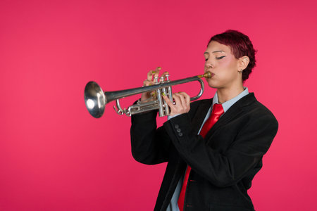 Musician playing trumpet against pink backgroundの写真素材