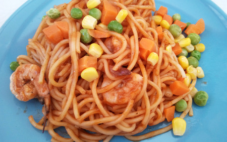 Delicious spaghetti puff with shrimp and tomato sauce in the blue plate, Close up on white background.の写真素材