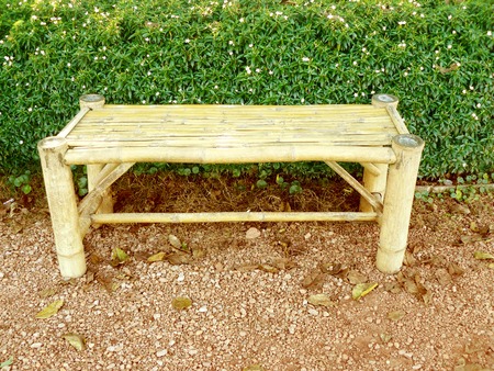 An old weathered bamboo bench in the garden with a hedge as a backdrop.の写真素材