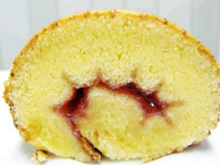 Close up front of roll cake vanilla with strawberry jam white plate.の写真素材