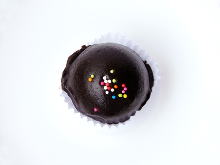 Close Up of chocolate ball with colorful sugar topping in paper cup and white plate isolated on white background.の写真素材