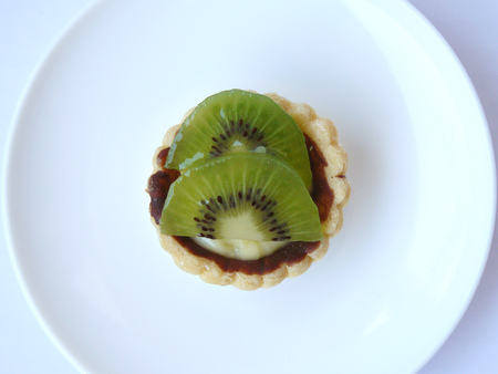 Delicious of Homemade fruit tart. Close up top view of dessert mini Kiwi fruits tart on a white plate isolated on white background.の写真素材