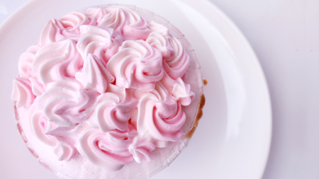 Princess Pink cupcake. Close up top view of cute cupcake decorated with pink creamy in a white plate. Isolated on white background.の写真素材