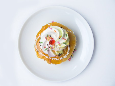 Close up the top view of orange vanilla cream cake. Circle small size of vanilla cake decorated with orange jam and cream on the top of cake. Putting on white plate, Isolated on white background.の写真素材