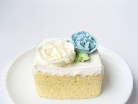 Close up front view of Chiffon snow flower cake. The chiffon vanilla cake decorated with cream of flower blue and white on the top of cake. Putting on white plate, Isolated on white background.の写真素材