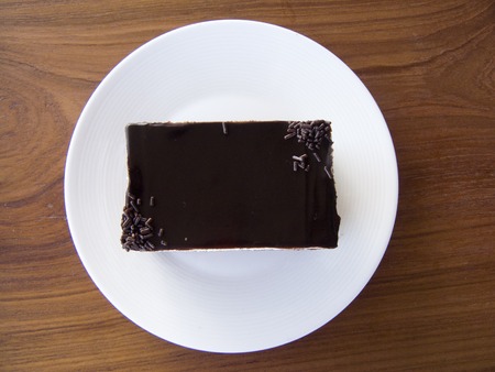 Close up top view of layer Chocolate Banana Cake or banoffee cake in a white plate on wooden table background.の写真素材
